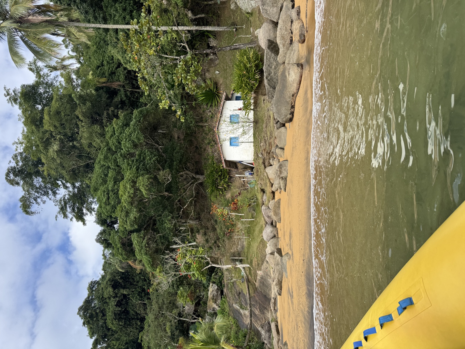 Blick vom Boot auf ein Strandhaus zwischen Palmen